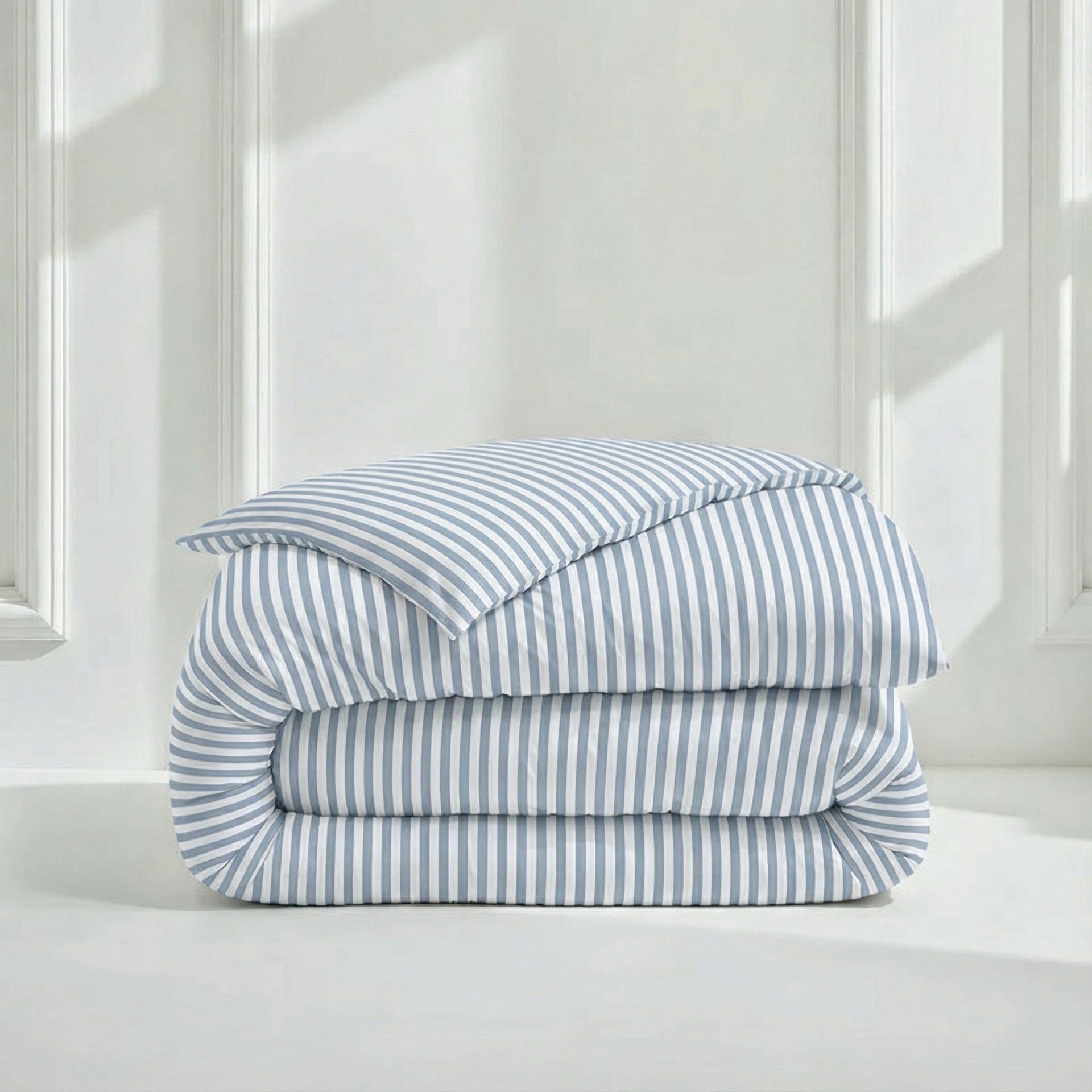 Folded stack of Australian Cotton Sateen Duvet Covers showing striped and solid lavender options in a bright, clean bedroom setting.