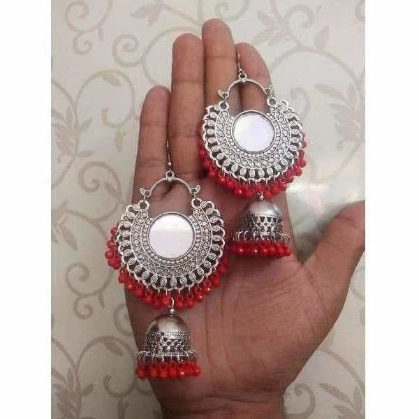 Pair of traditional Indian oxidized jhumka earrings with red beads and intricate metalwork.