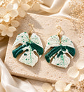 Abstract Monstera Bulbasaur polymer clay earrings in green and white.