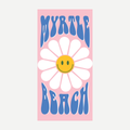 A rectangular beach towel with a pink background featuring a large white daisy with a yellow smiley face in the center and blue text reading Myrtle Beach above and below.