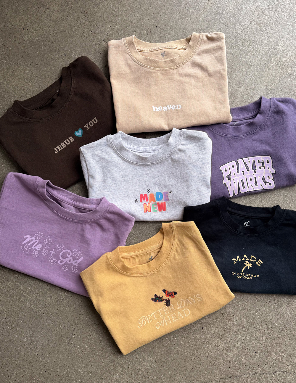 A variety of kids' oversized cotton tees in assorted solid colors folded neatly