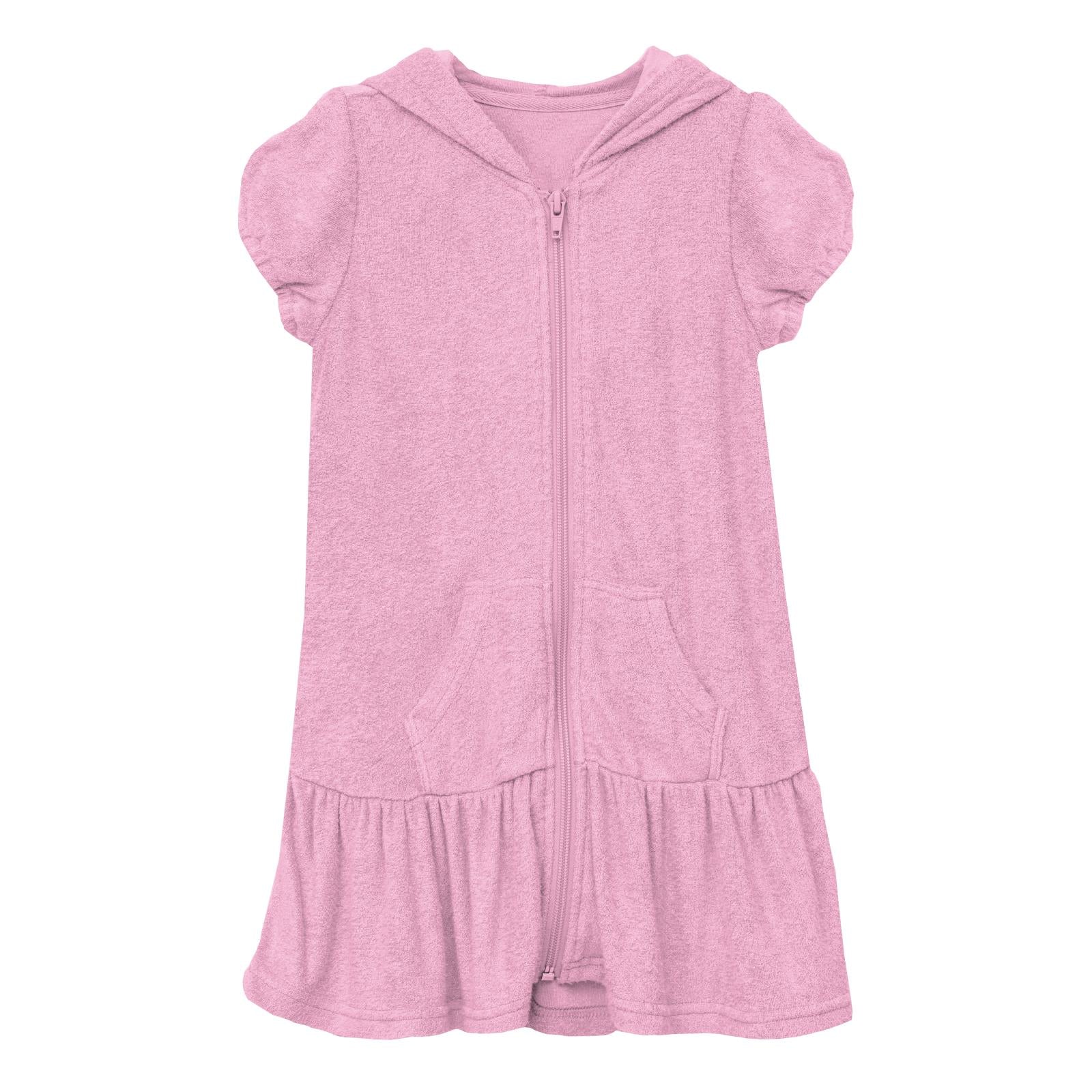 Woman wearing a bright bubblegum pink terry ruffle swim cover-up on a sunny beach day.