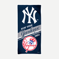 A navy blue New York Yankees velour beach towel featuring the team logo, text, and baseball graphic.