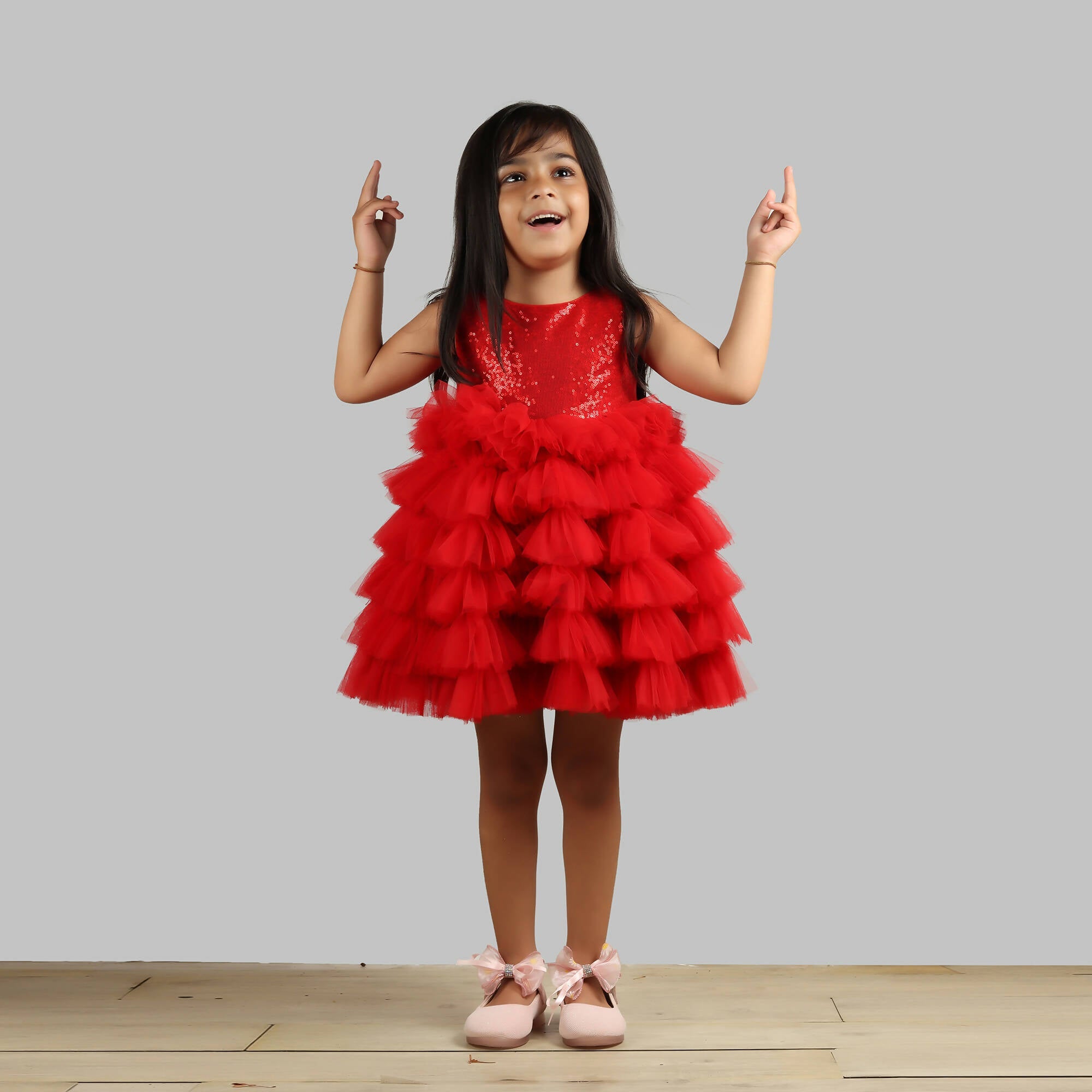 Girl wearing a vibrant red dress with a sequin bodice and layered frill bottom