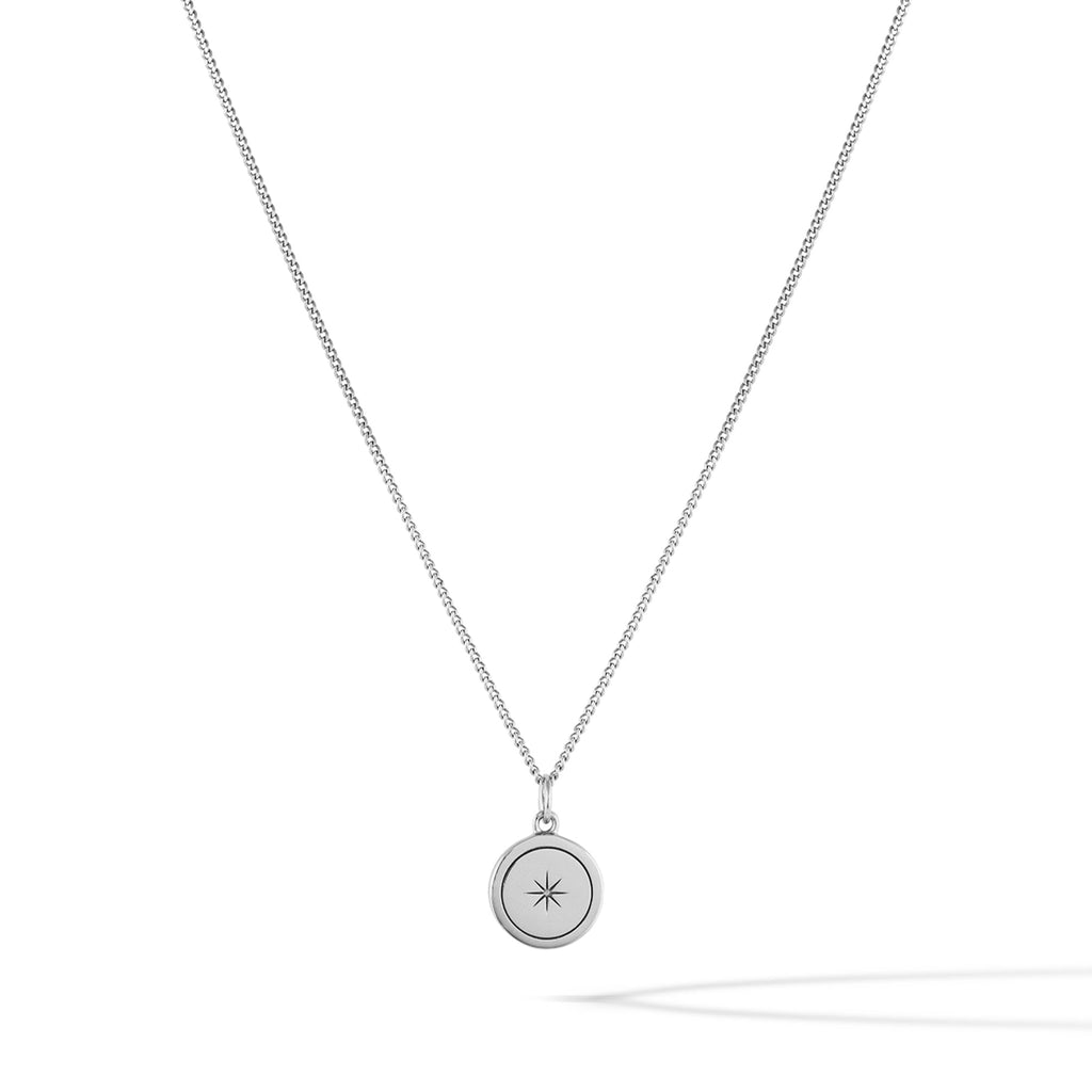 Close up of a North Star pendant necklace in sterling silver on a minimalist background