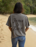 Model wearing a charcoal Jesus Is King heavyweight cotton boxy tee in a minimalist streetwear style