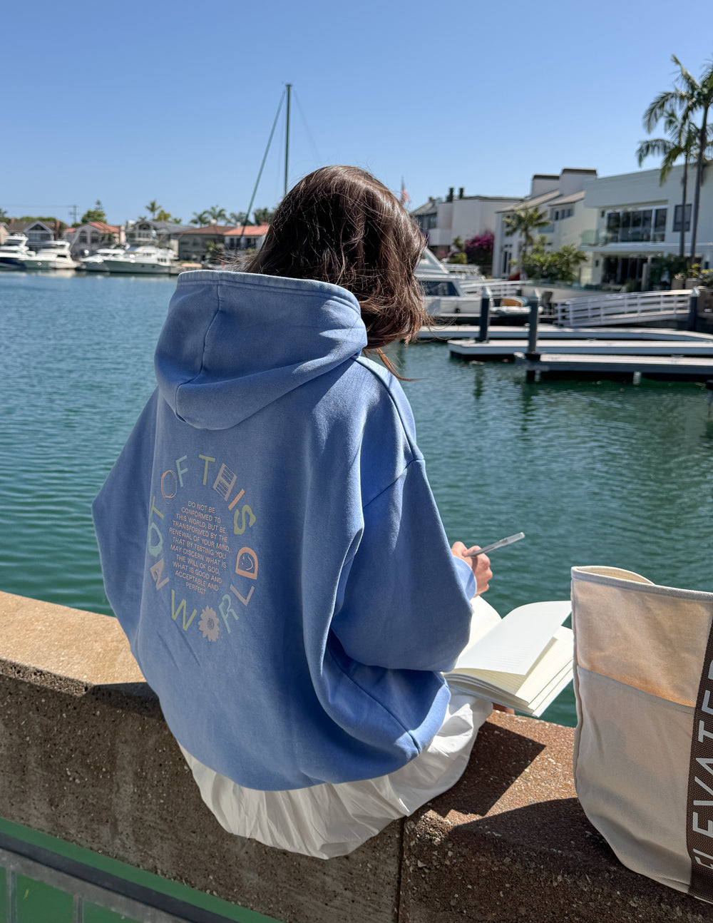 Model wearing a pigment-dyed Provence Blue unisex hoodie with faith-based graphic lettering