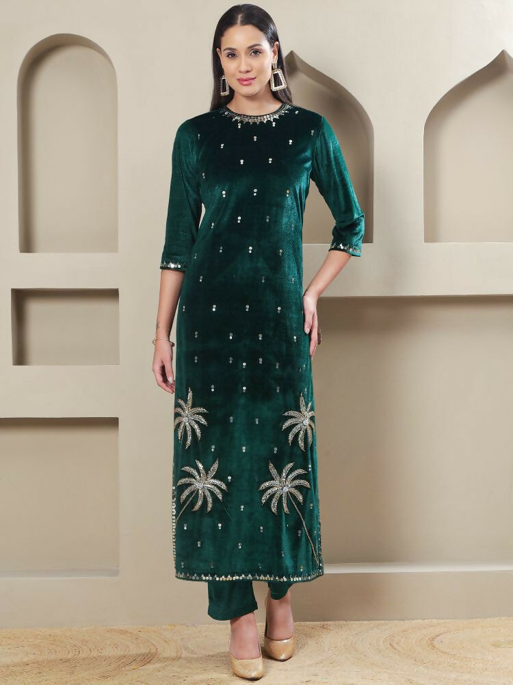 Woman wearing a luxurious green velvet kurta set with intricate hand embellishments and matching pants