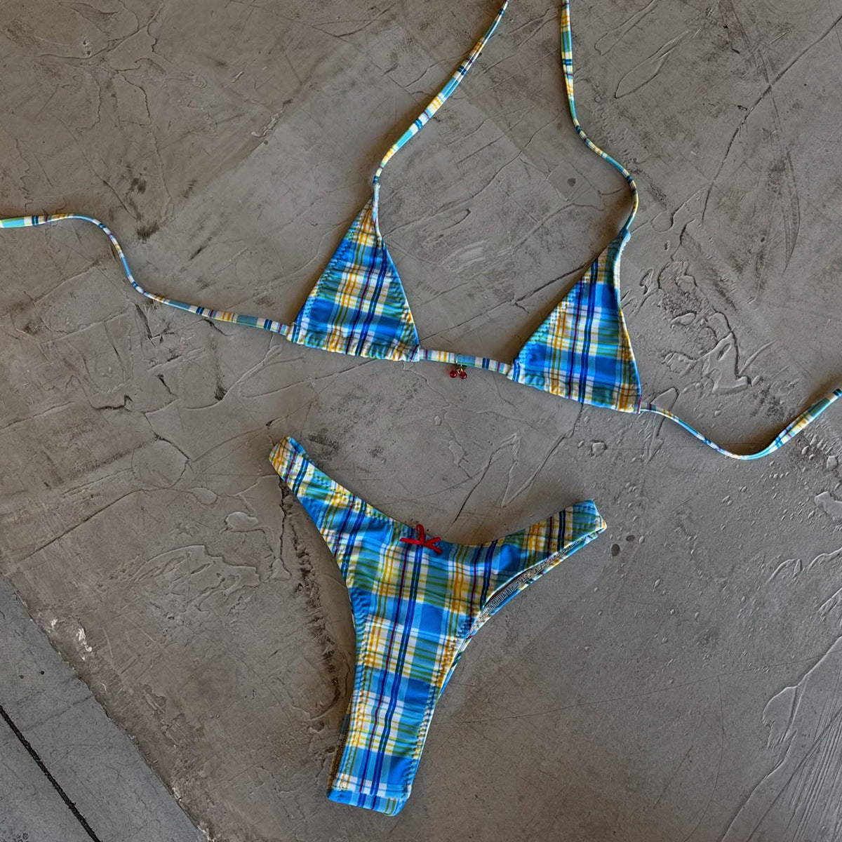 A colorful geometric print bikini with halter straps, bows, and ruched tie-side bottoms in blue, yellow, and white.