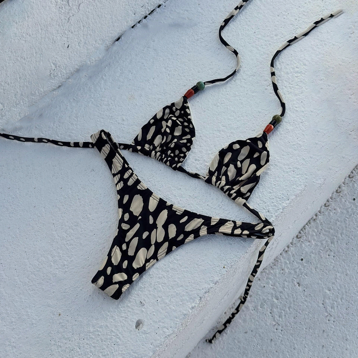 A two-piece bikini featuring an abstract print in black and cream with halter tie straps