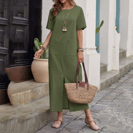 A woman wearing a solid color cotton linen midi dress with round neck and pockets in a muted earth tone.