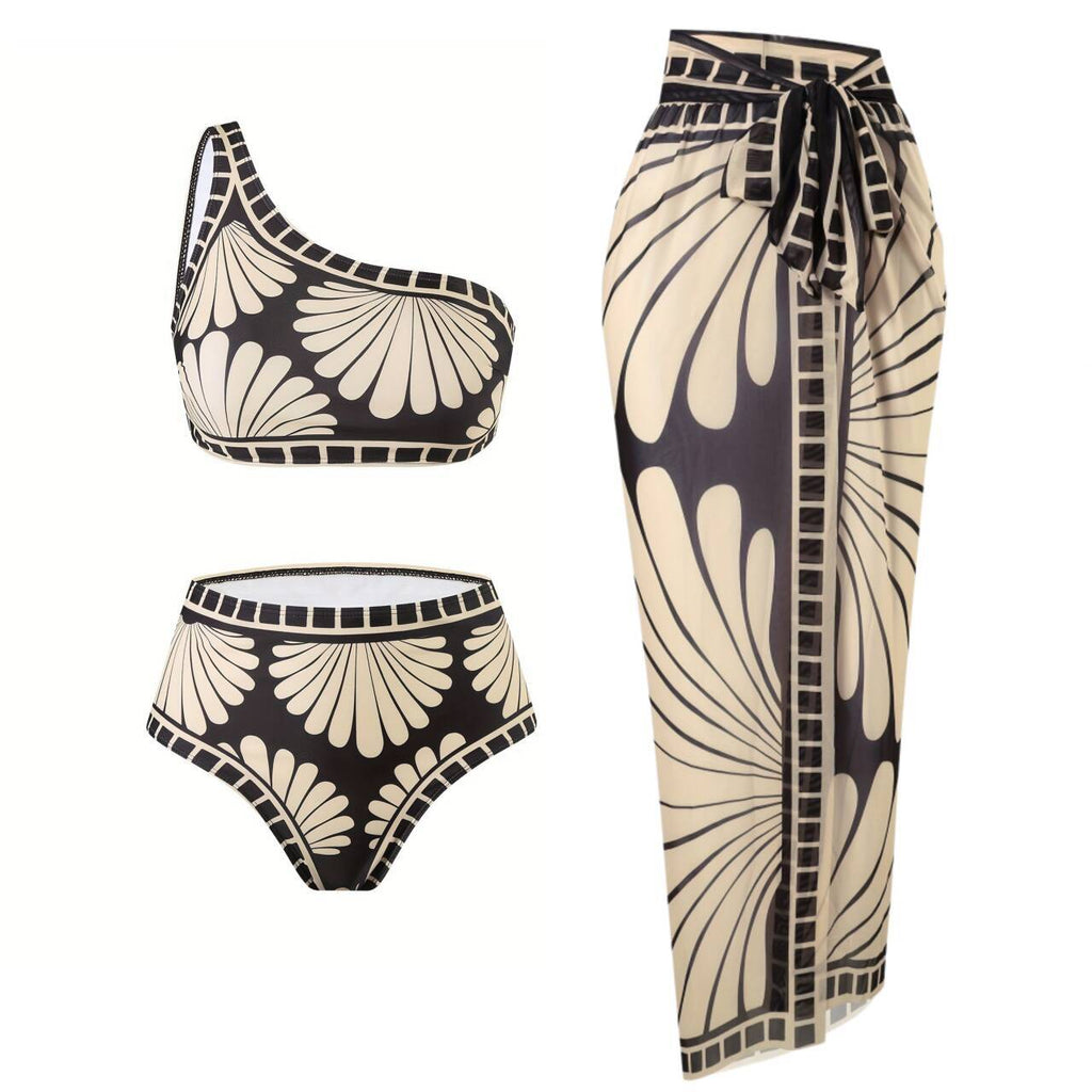 Woman wearing a black and beige geometric print three-piece bikini set with an oblique shoulder strap and matching skirt.
