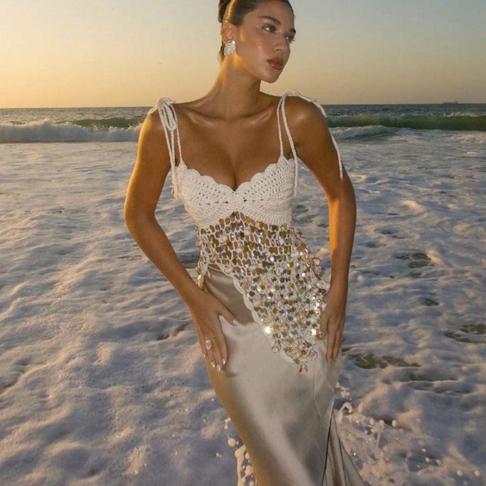 A woman wearing a sleeveless, backless sequin beach dress with an asymmetric tie detail.