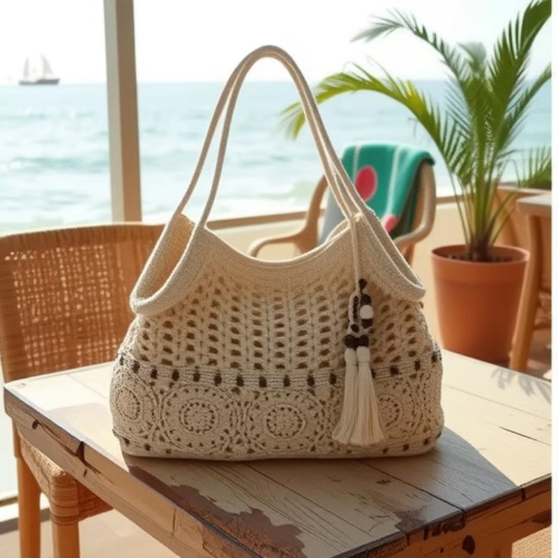 A beige woven cotton shoulder bag featuring a hollow-out pattern, decorative wooden beads, and hanging tassels, styled for a beach vacation.