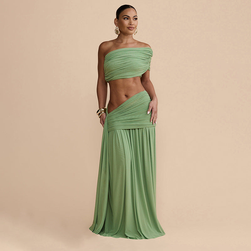 Model wearing a Bella Mia solid green ruched off-shoulder crop top and matching low-rise asymmetric pleated maxi skirt.
