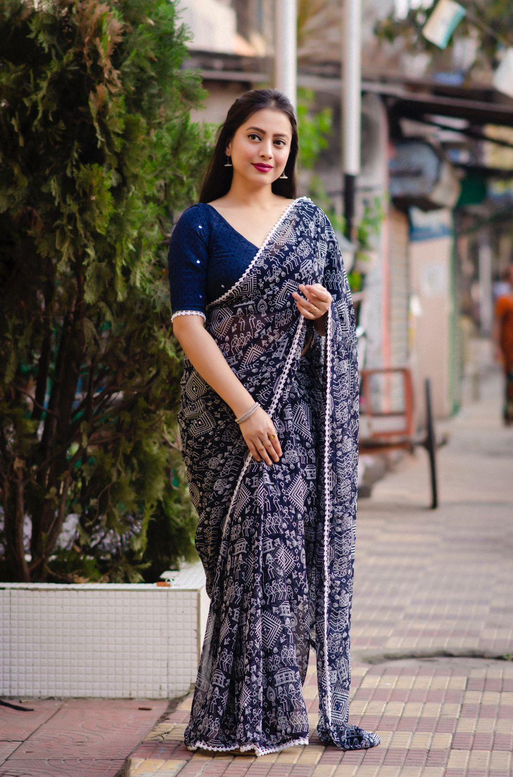 Blue poly georgette saree with intricate Warli prints and Aari mirror work border.