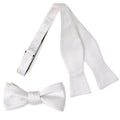A classic white silk self-tie bow tie displayed next to its adjustable strap, and a second image showing the bow tie styled with a grey suit jacket.