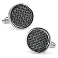 A pair of round black woven metal cufflinks with polished silver edges worn on a dress shirt cuff