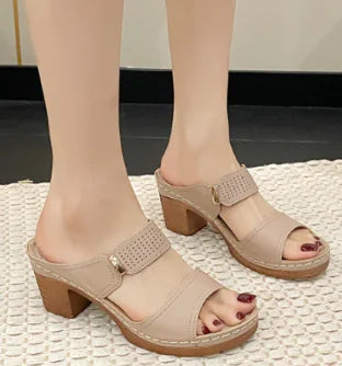 A pair of women's chunky heel sandals in beige with a perforated top strap.