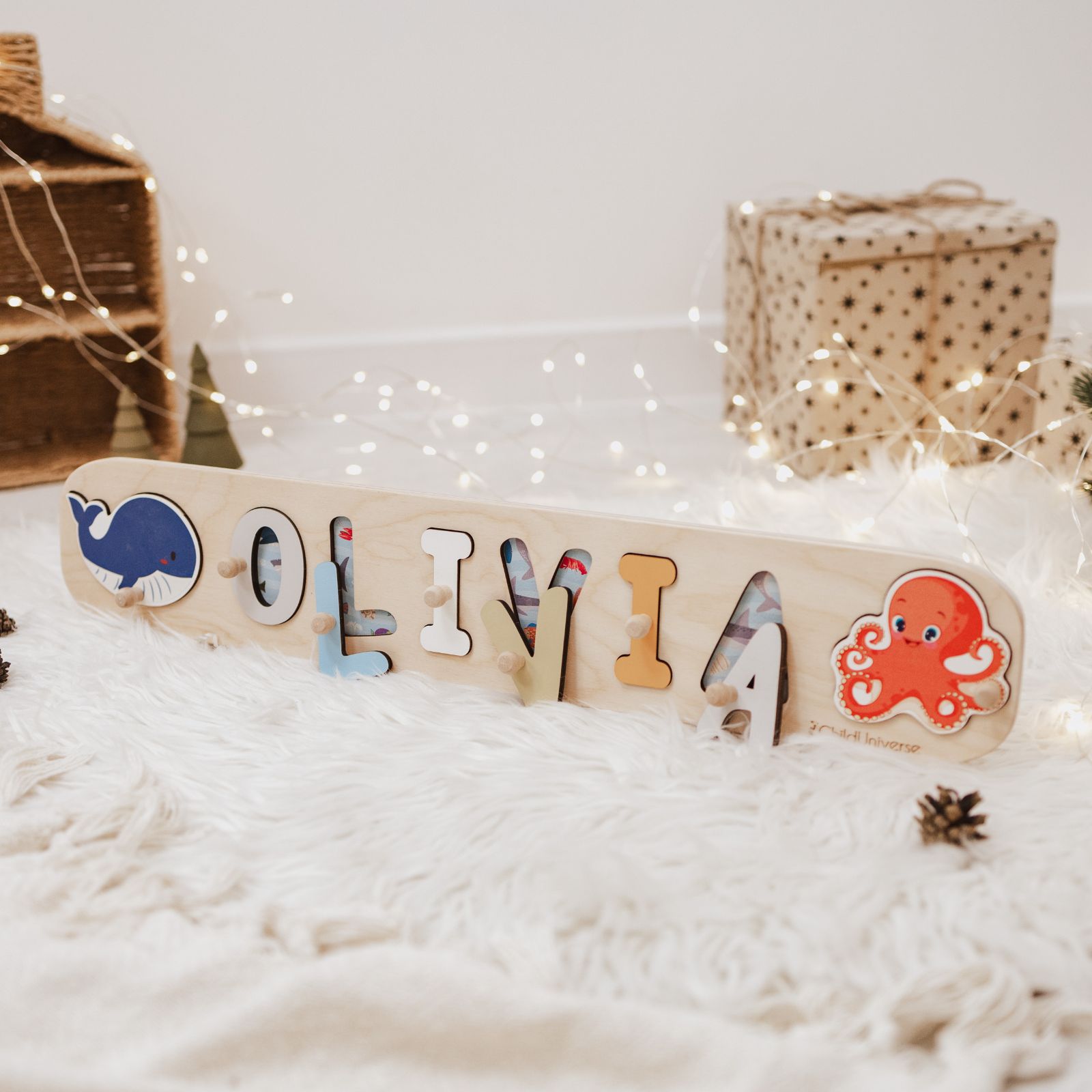 Wooden name puzzle with ocean animals including a whale and octopus on a light-wood background in a nursery setting.