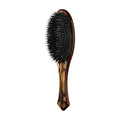 Modern flat hair brush featuring a brown tortoiseshell pattern and black bristles displayed on a minimalist surface.