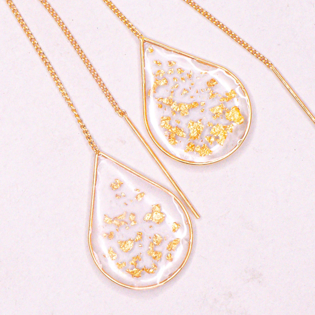 Close-up of Anh Thư gold ear threaders showing polished finish.