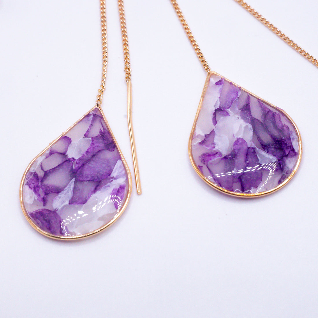 Mộng Huyền abstract ear threaders in purple, white, gold, and silver tones.