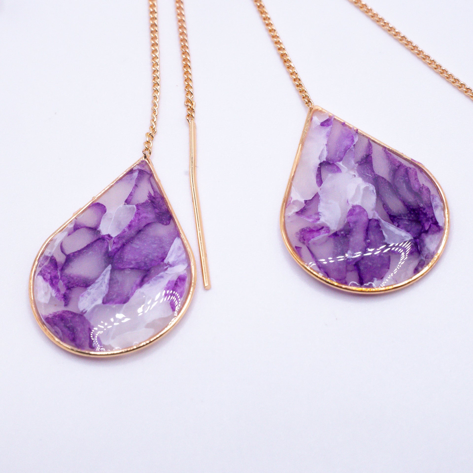 Mộng Huyền abstract ear threaders in purple, white, gold, and silver tones.