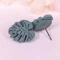 Mini Monstera studs in earthy green with a matte finish.