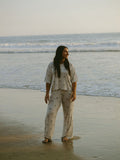 Woman wearing a matching palm tree print lounge set with a boxy t-shirt and wide-leg pants standing on a beach at sunset