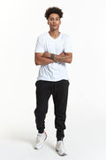 A man wearing solid black fleece jogger sweatpants with ribbed cuffs and a drawstring waist.