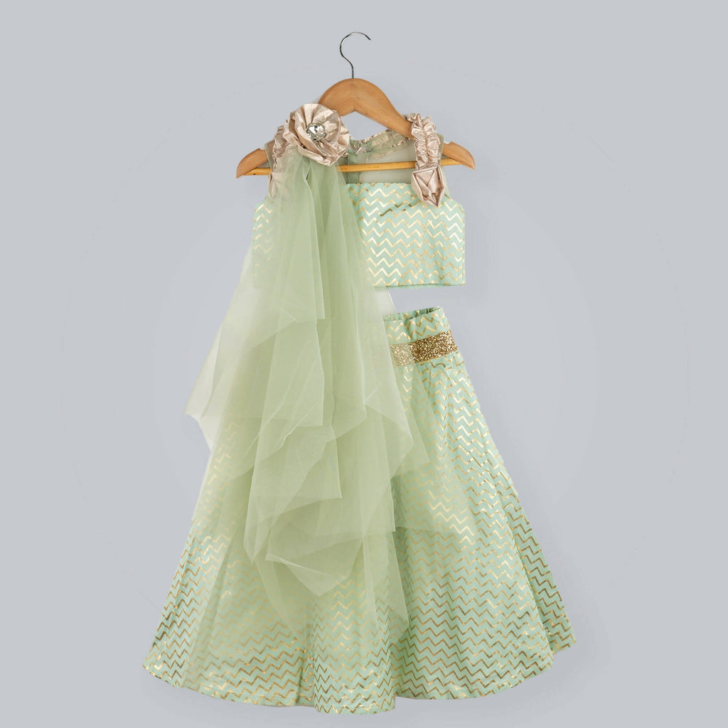 Girl wearing green zig-zag printed ghagra choli with gold lame frill strips and net dupatta.