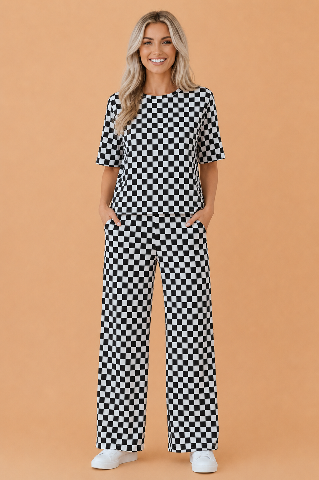A woman wearing a matching black and white checkerboard print lounge set with a crew neck tee and wide-leg pants.
