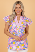 A woman wearing a vibrant floral print v-neck blouse with flutter sleeves and striped trim details.