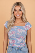 Woman wearing a floral mesh ruched top with a square neckline and cap sleeves in pastel blue