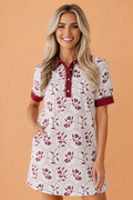 Woman wearing a white and maroon floral geometric print mini dress with collared neckline and lace trim details.