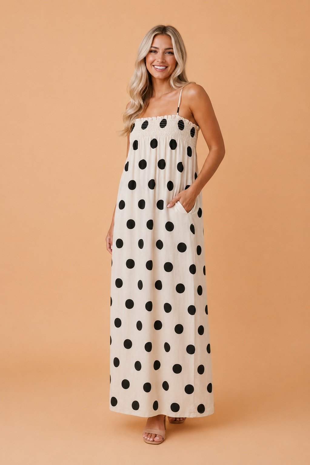 Woman wearing a beige and black polka dot maxi dress with square neckline and adjustable spaghetti straps