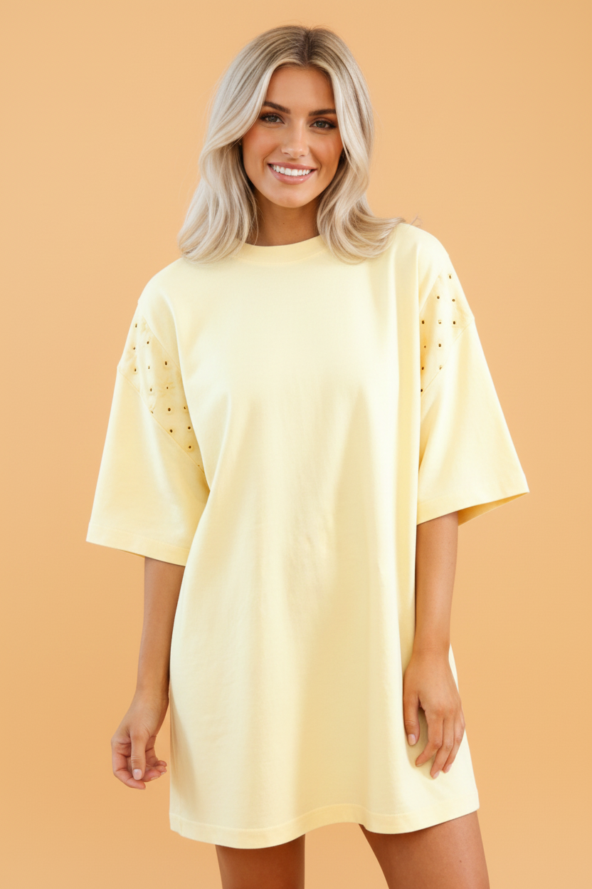 A pale yellow cotton T-shirt dress featuring intricate eyelet patchwork and lace detailing with pockets.