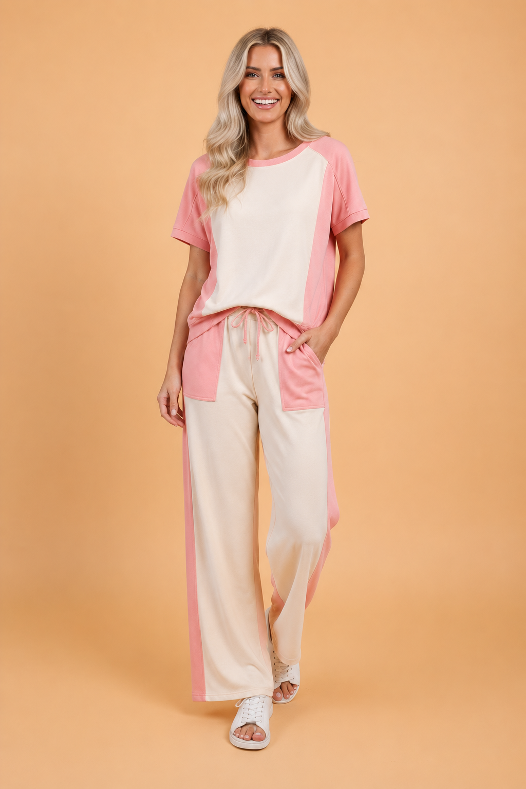 Woman wearing a dusty pink and cream geometric colorblock knit loungewear set with a crew neck tee and wide-leg drawstring pants.
