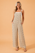 A woman wearing a beige and multicolor floral print spaghetti strap maxi jumpsuit with a relaxed, wide-leg fit.