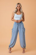 A model standing wearing light blue denim jogger pants with a drawstring waist and side pockets.