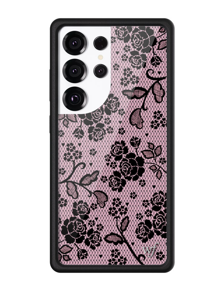 Close-up of a Samsung Galaxy phone case featuring a blush pink background with a detailed black floral lace print and black protective edges.