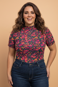 A woman wearing a vibrant floral mesh short sleeve top in pink, orange, green, and black.