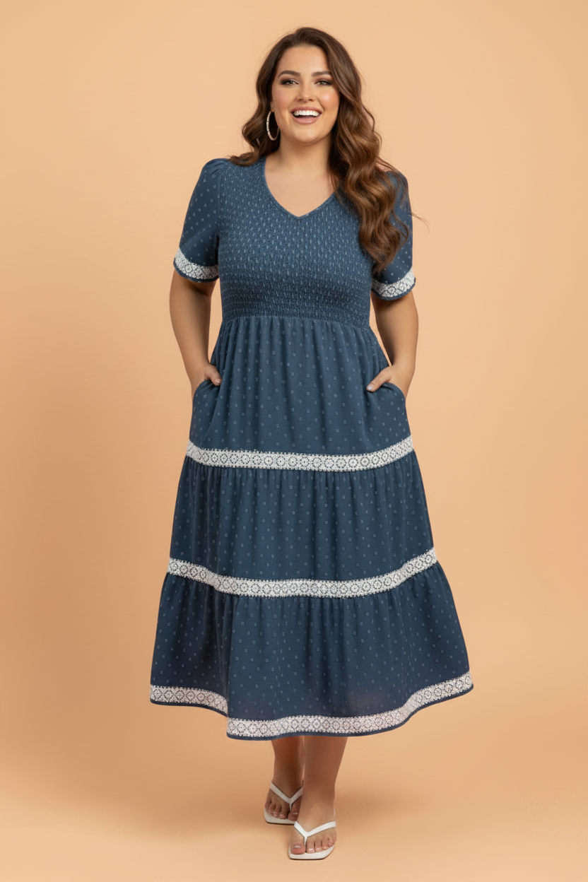 Navy blue midi dress with white swiss dot pattern, lace trim, and smocked v-neck design