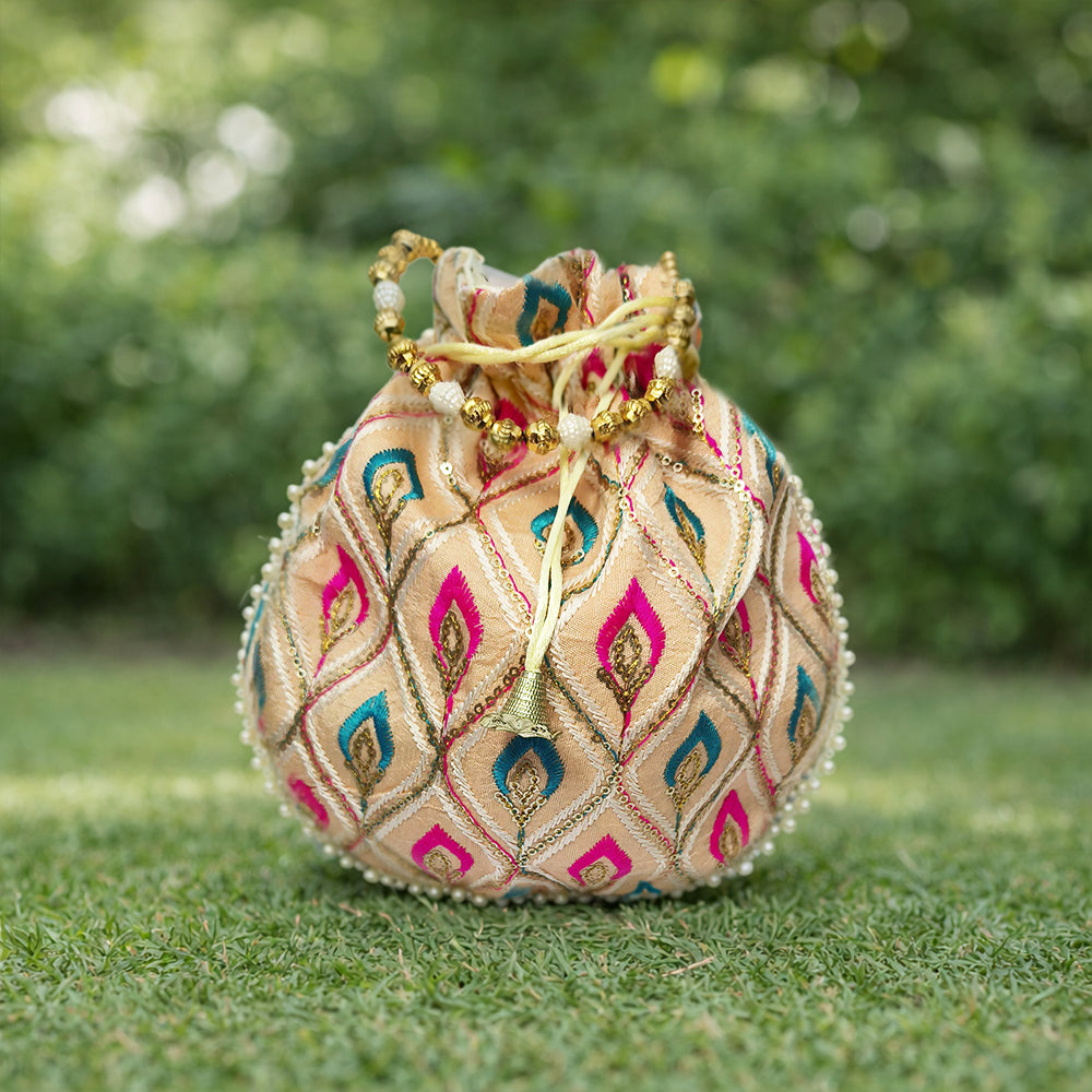 Close-up of a handcrafted wedding potli bag with intricate embroidery, pearl borders, and beaded handle.