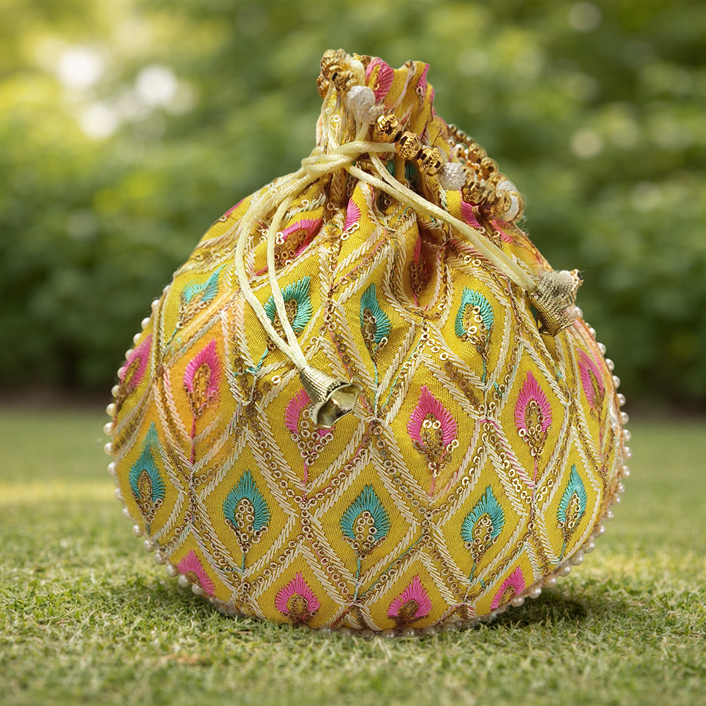 Close-up of a handcrafted wedding potli bag with intricate embroidery, pearl borders, and beaded handle.