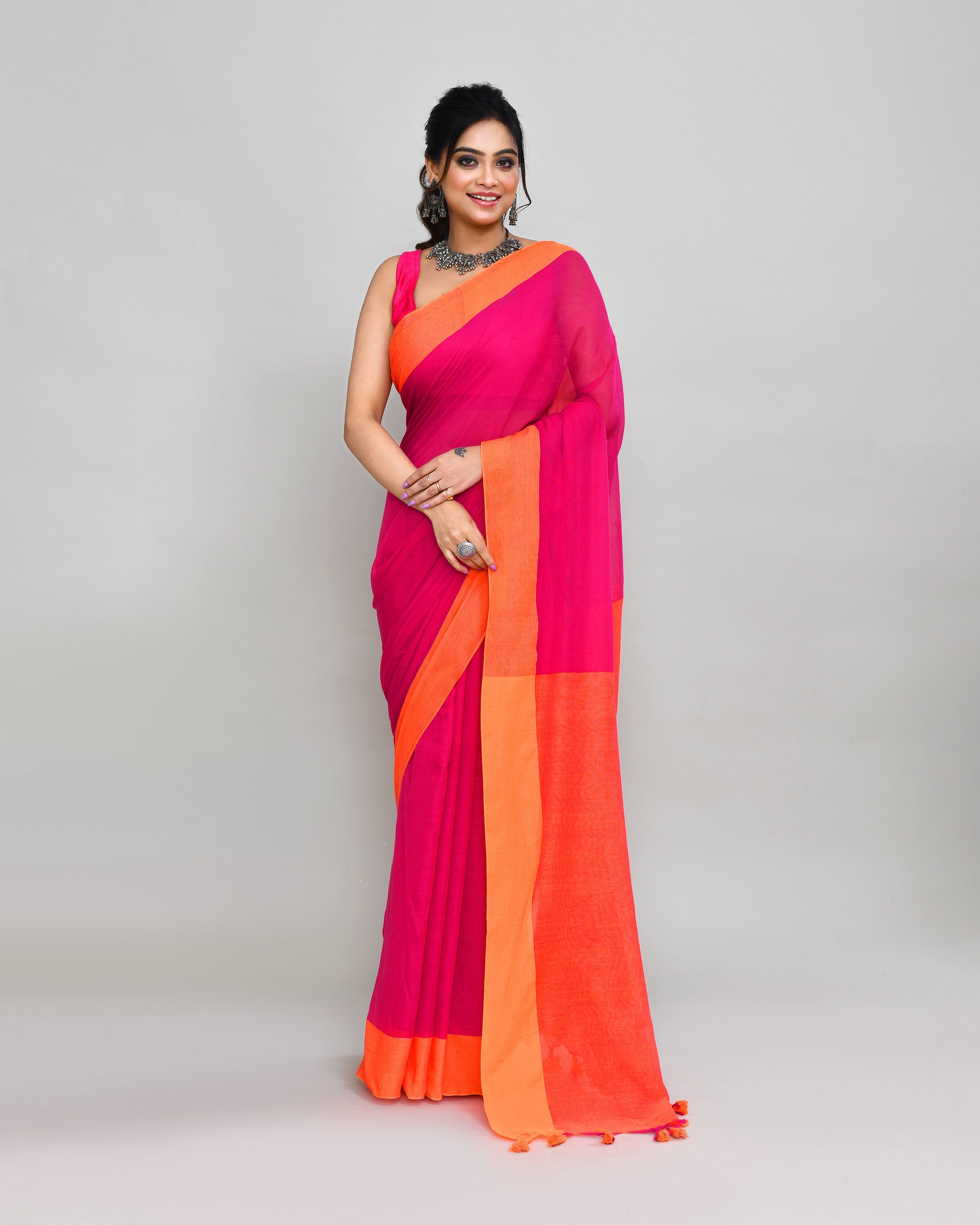 Rani Pink cotton saree with orange border and tassel details draped elegantly