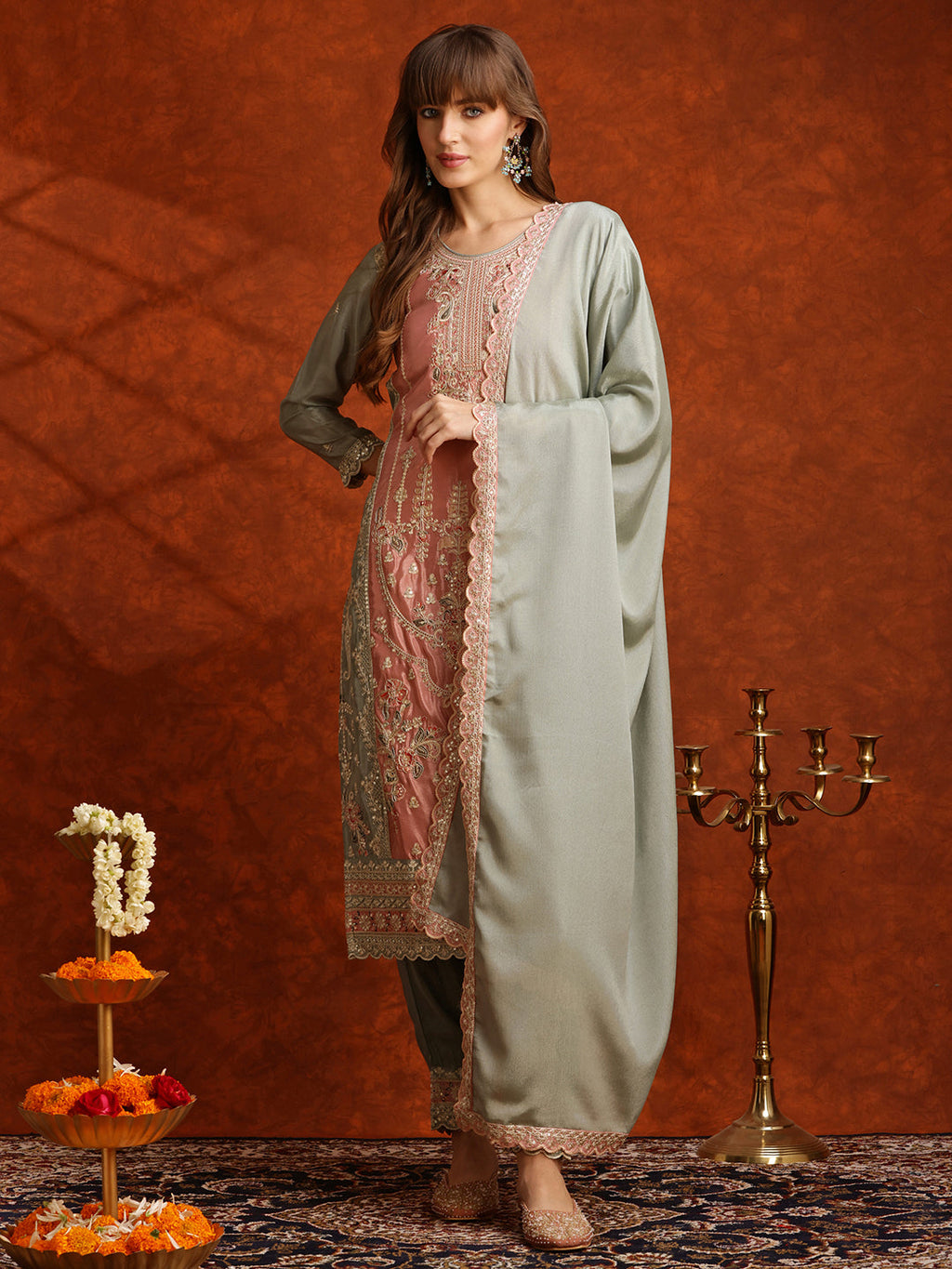 Model wearing a green Pakistani embroidered silk kurta set with matching pants and dupatta
