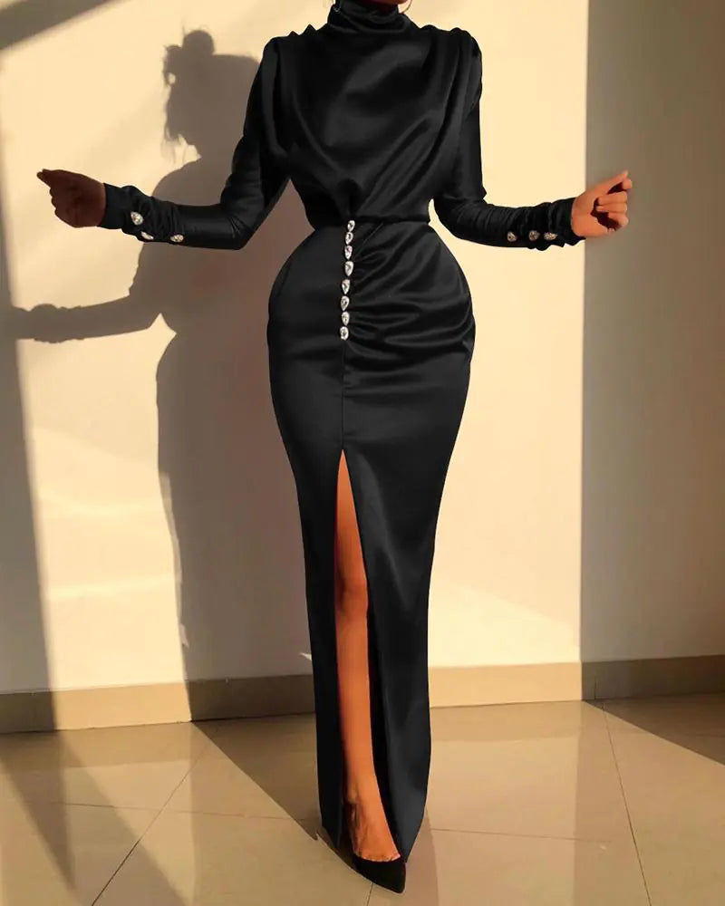 A woman wearing a long sleeve high neck maxi dress with a front leg split in black and burgundy