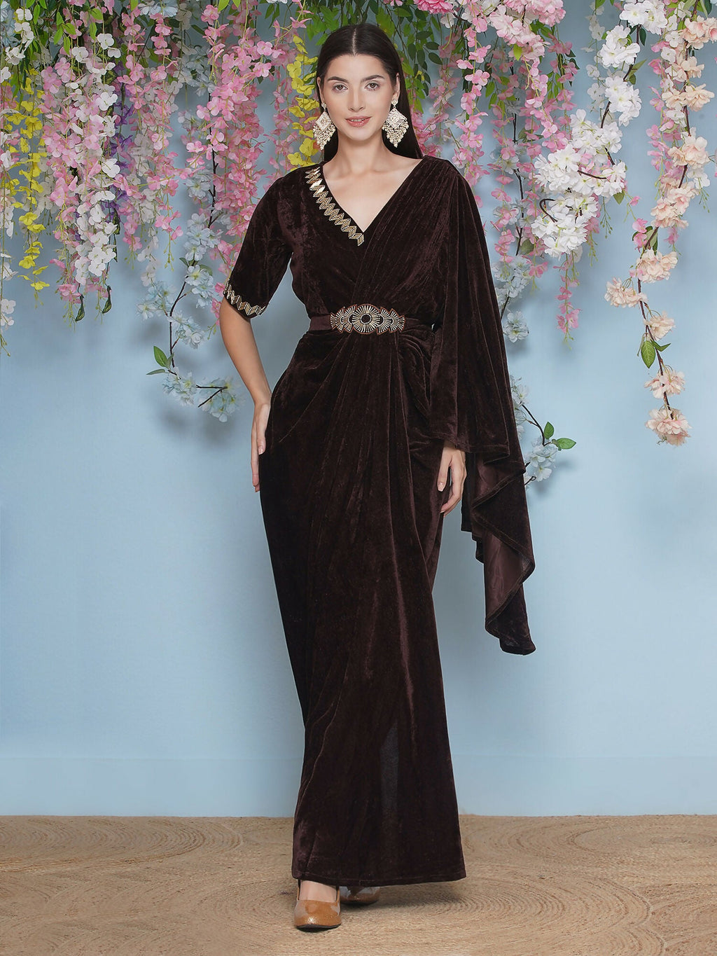 A luxurious brown velvet gown featuring intricate hand embellishments, a graceful drape, and a coordinating belt.